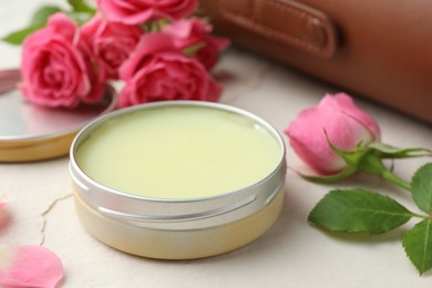 Photo of Natural solid perfume in container and pink roses on white table, closeup