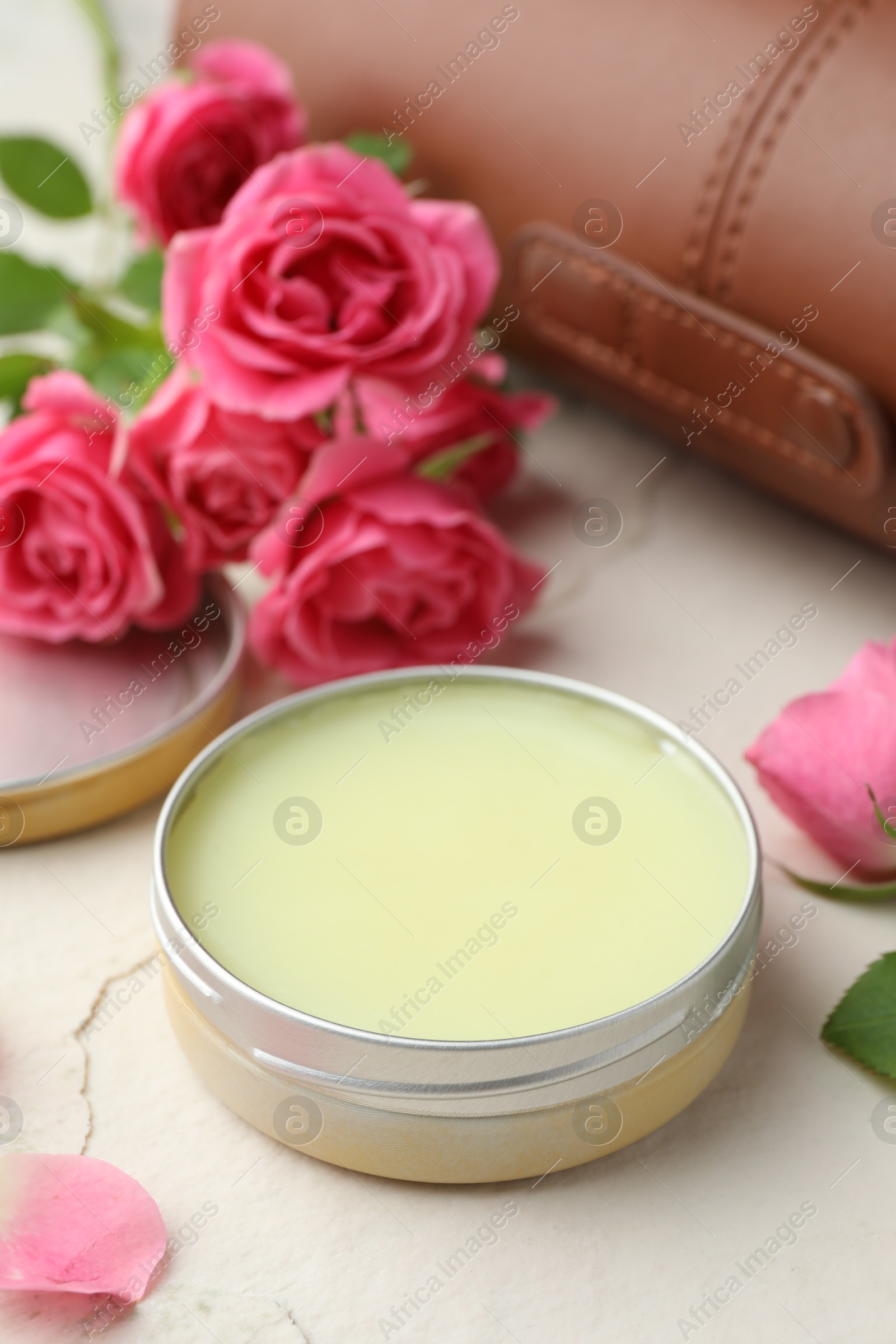 Photo of Natural solid perfume in container and pink roses on white table, closeup