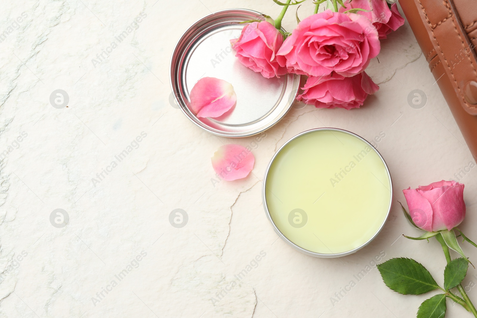 Photo of Natural solid perfume and pink roses on white textured background, flat lay. Space for text