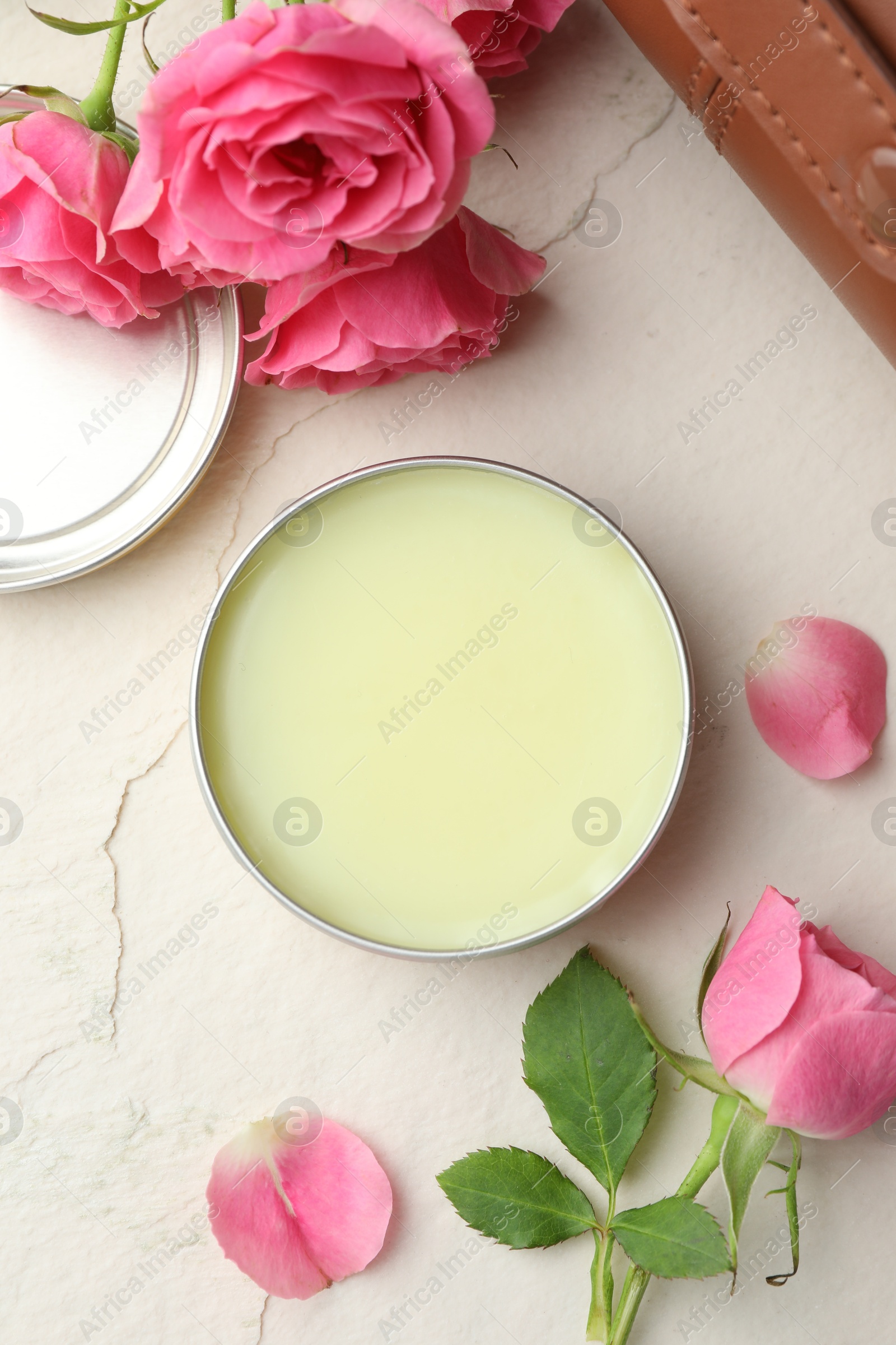 Photo of Natural solid perfume and pink roses on white textured background, flat lay