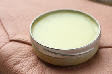 Photo of Natural solid perfume in container on leather surface, closeup