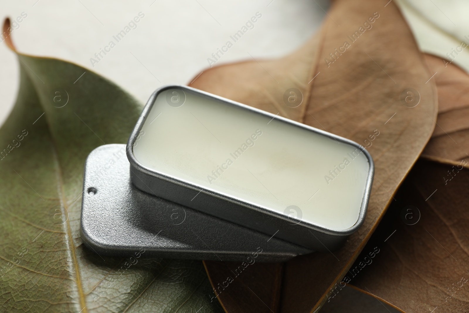 Photo of Natural solid perfume and leaves on white table, closeup