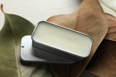 Photo of Natural solid perfume and leaves on white table, closeup