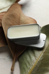 Photo of Natural solid perfume and leaves on white table, closeup