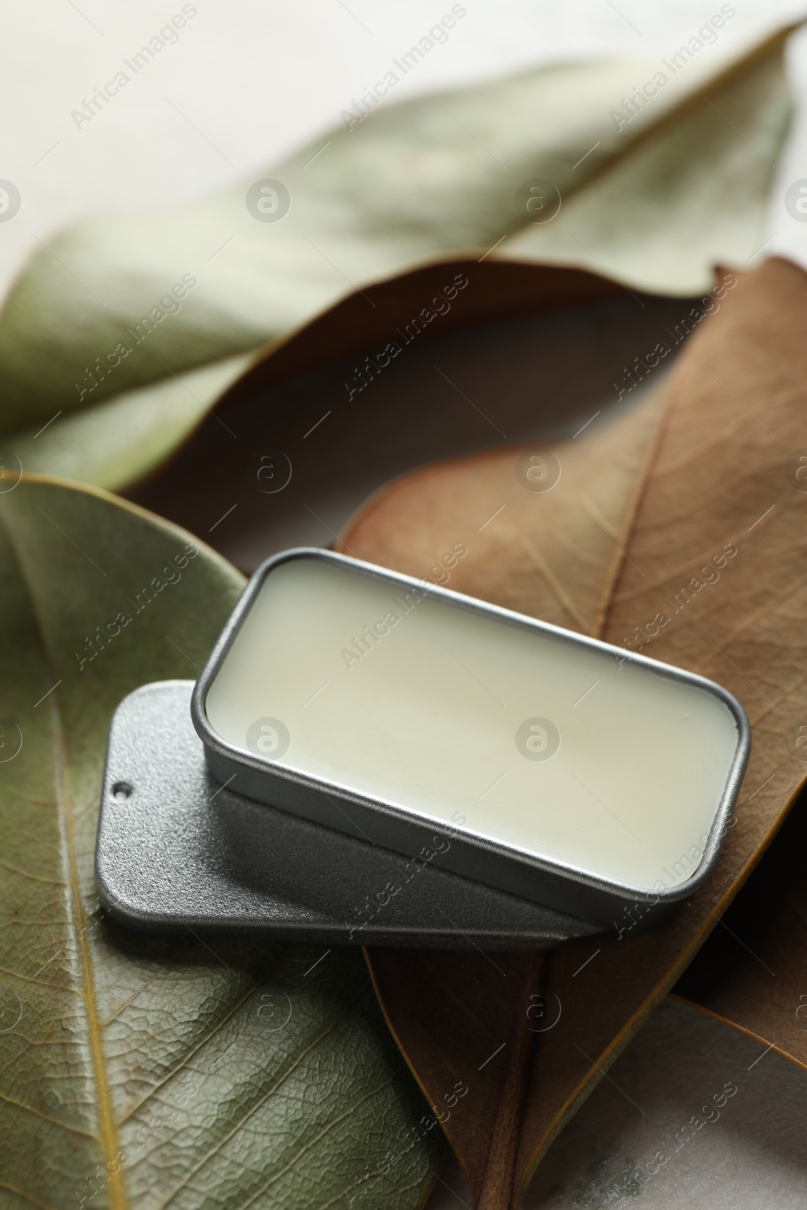 Photo of Natural solid perfume and leaves on white table, closeup