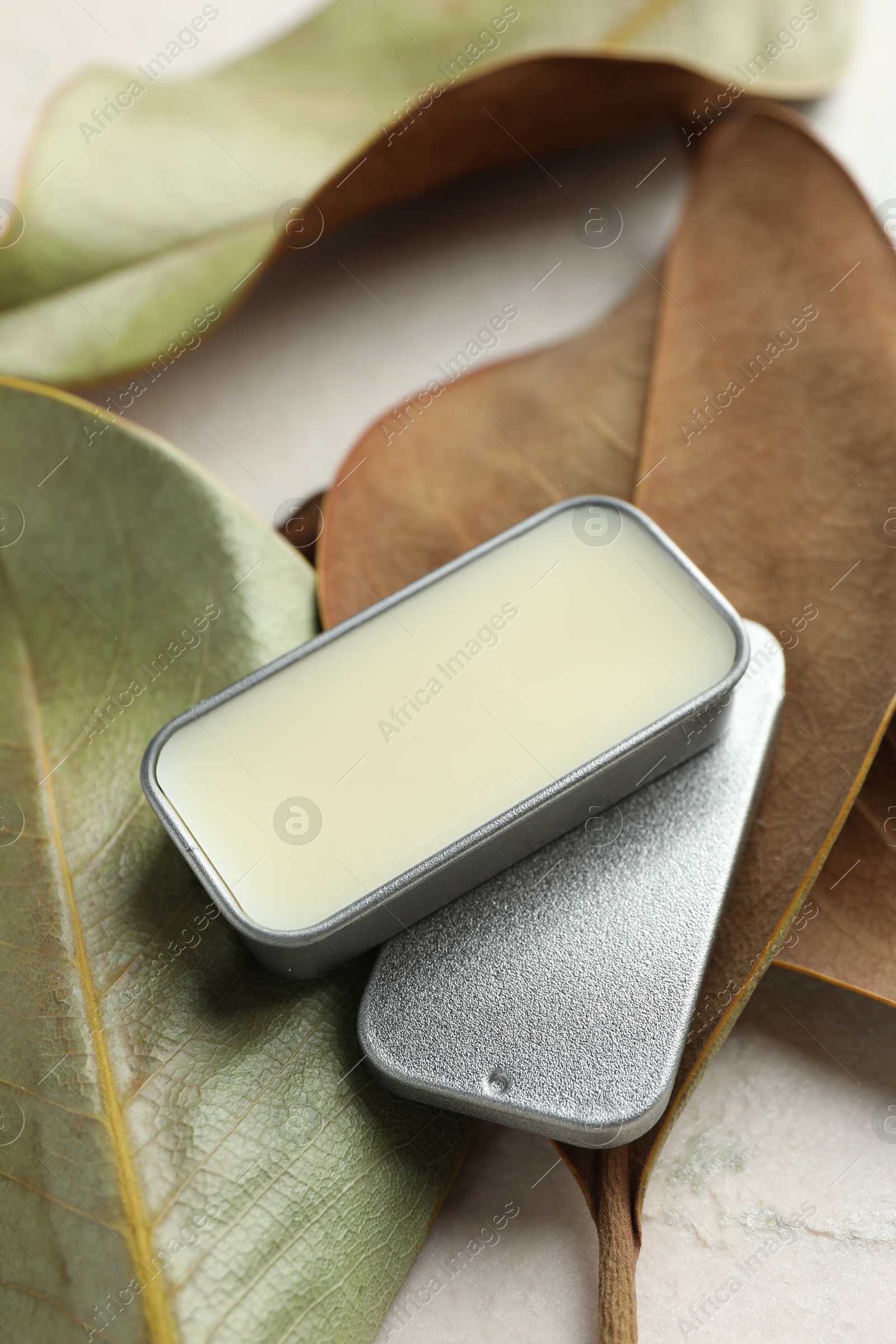 Photo of Natural solid perfume and leaves on white table, closeup