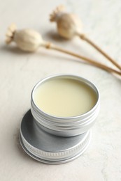 Photo of Natural solid perfume in container and plant on white table, closeup