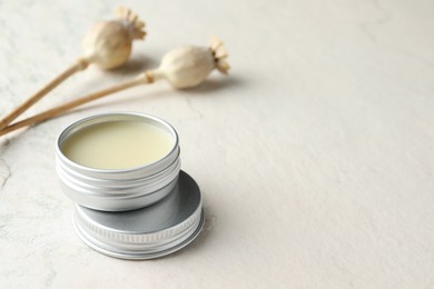 Photo of Natural solid perfume in container and plant on white table, closeup. Space for text