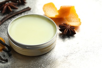 Natural solid perfume in container, vanilla pods, anise stars and orange peels on grey table, closeup. Space for text