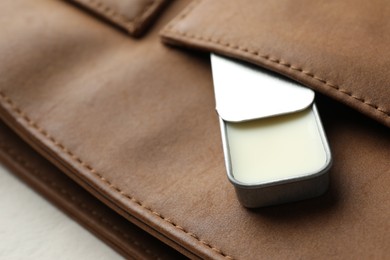 Photo of Natural solid perfume in container and leather bag on light table, closeup