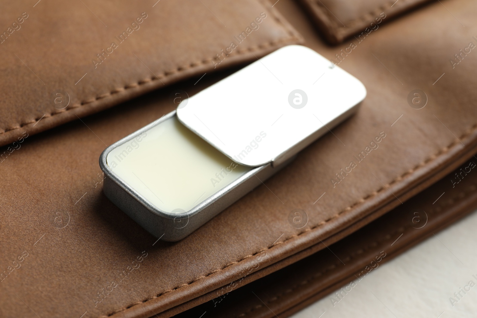 Photo of Natural solid perfume in container and leather bag on light table, closeup