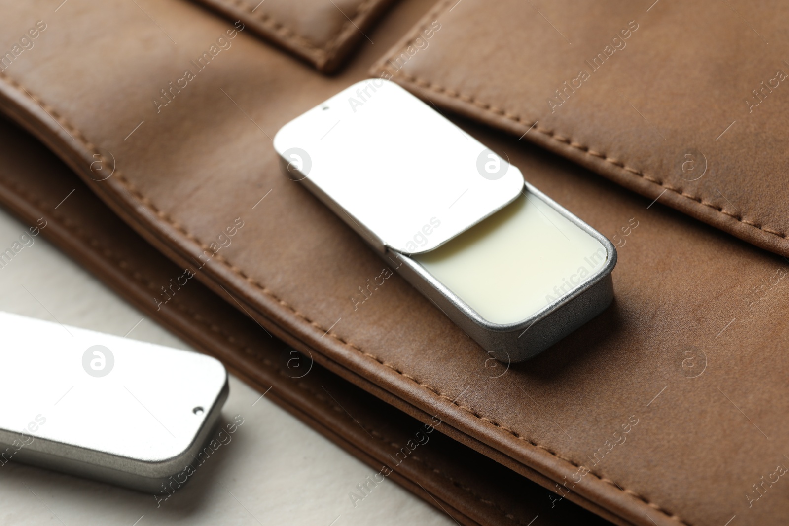 Photo of Natural solid perfume in containers and leather bag on light table, closeup