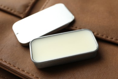 Photo of Natural solid perfume in container and leather bag on table, closeup