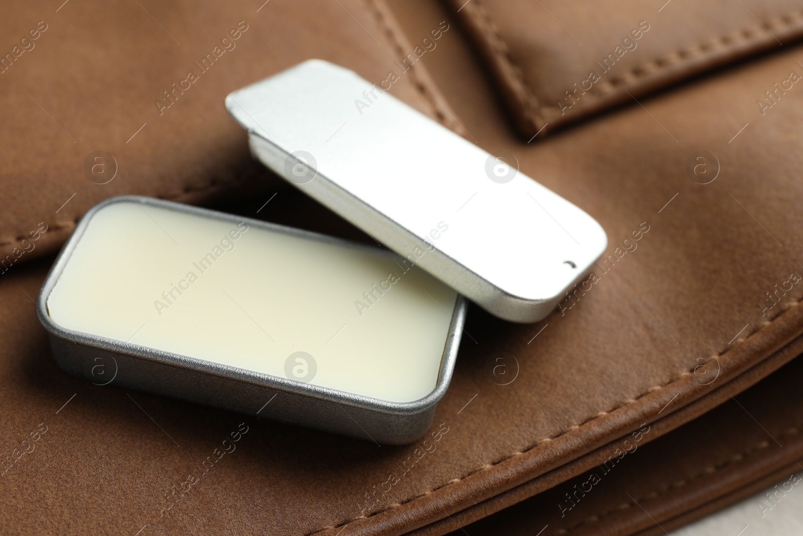 Photo of Natural solid perfume in container and leather bag on table, closeup