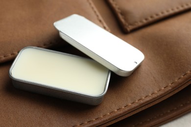 Photo of Natural solid perfume in container and leather bag on table, closeup