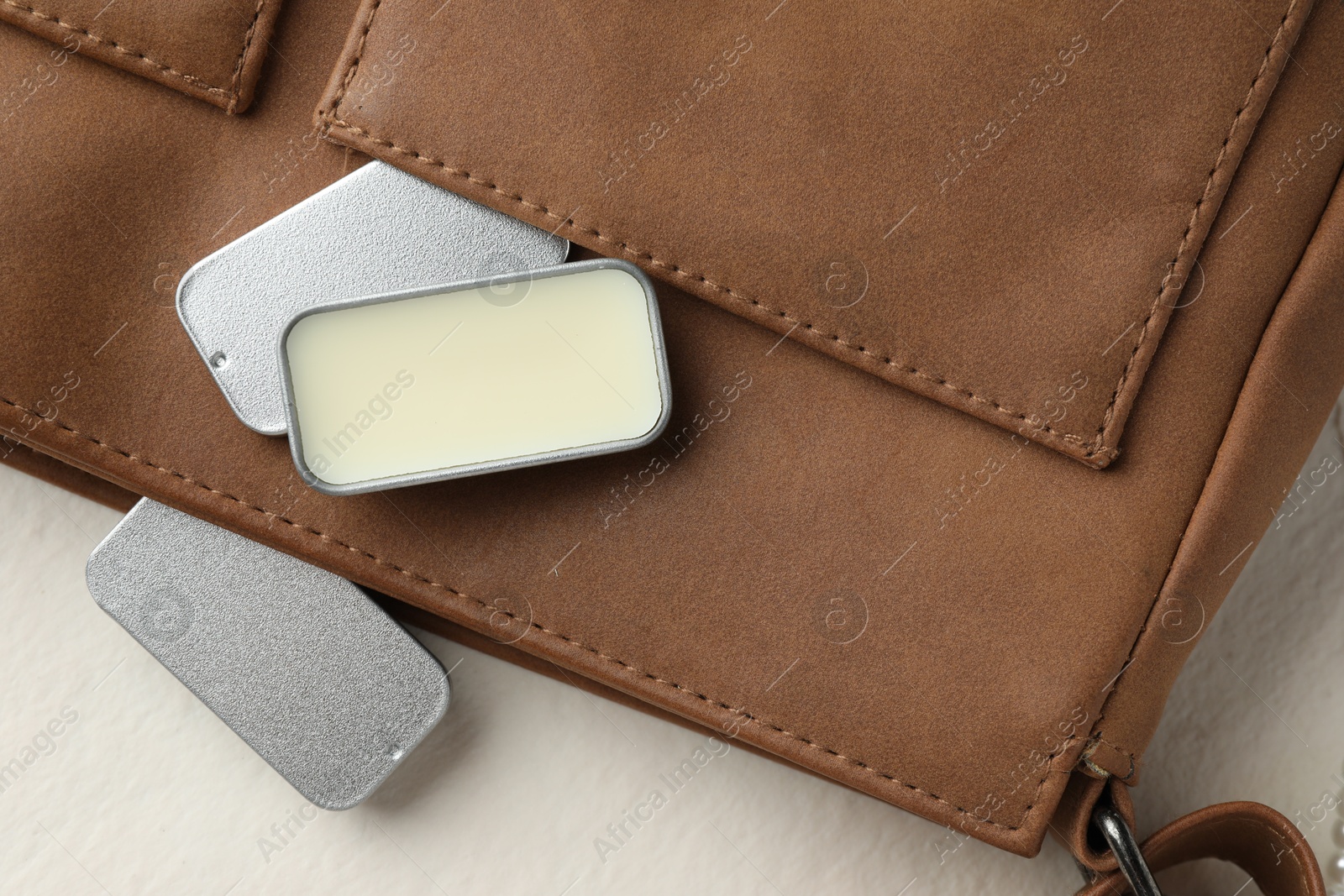 Photo of Natural solid perfume in containers and leather bag on light table, flat lay