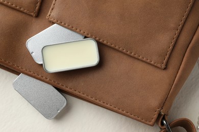 Photo of Natural solid perfume in containers and leather bag on light table, flat lay