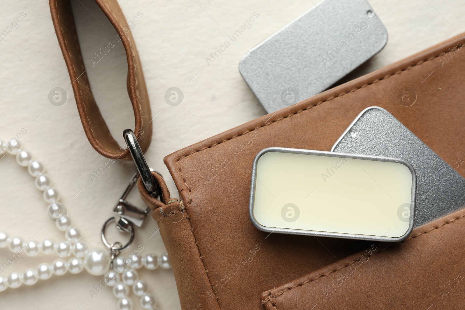 Photo of Natural solid perfume in containers and leather bag on light table, flat lay