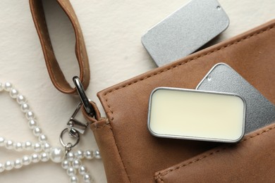 Photo of Natural solid perfume in containers and leather bag on light table, flat lay