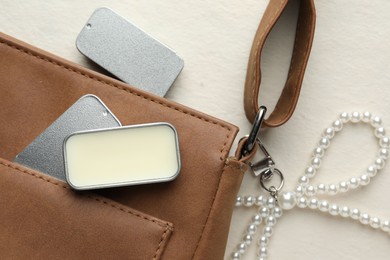 Photo of Natural solid perfume in containers and leather bag on light table, flat lay