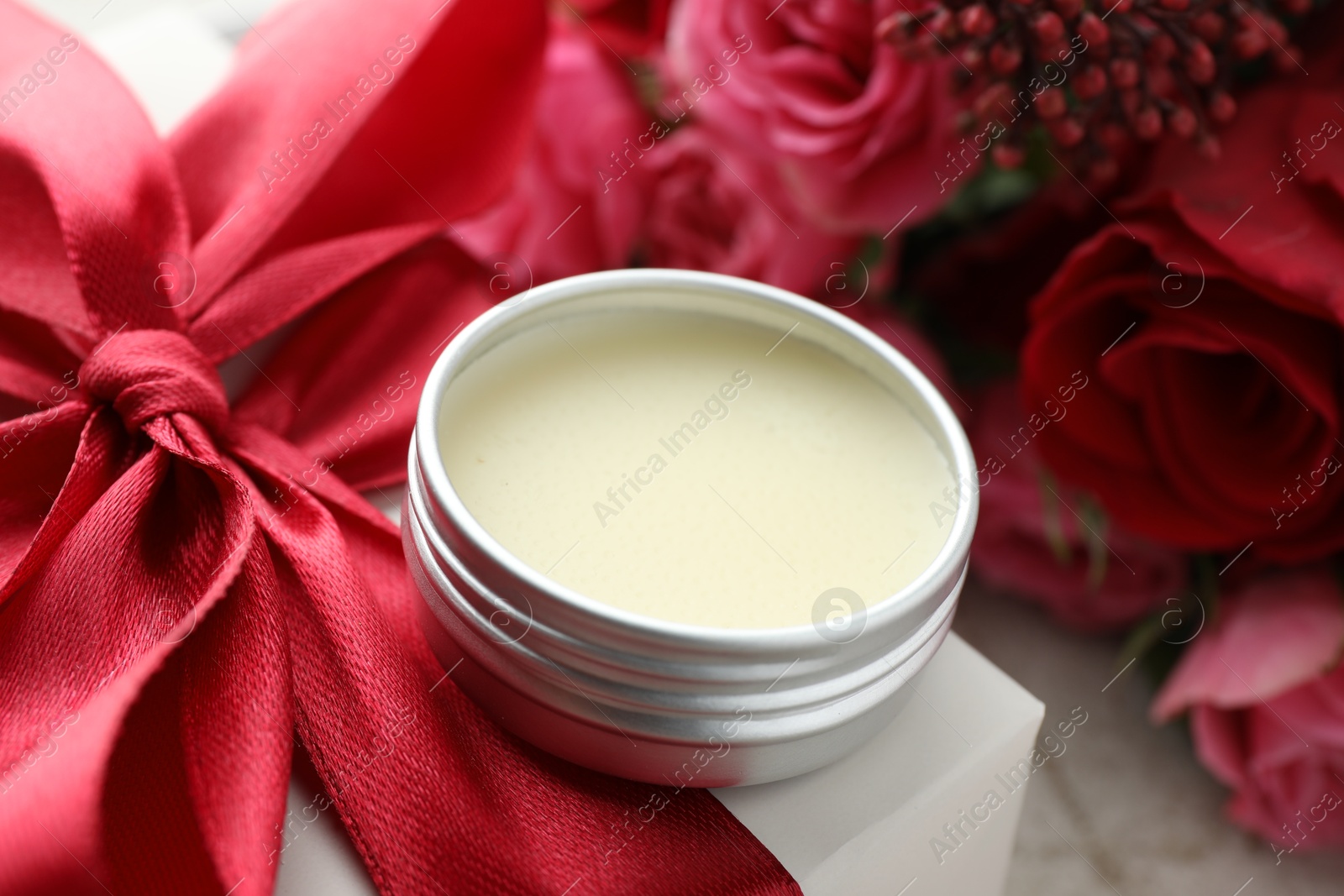 Photo of Natural solid perfume in container, gift box and flowers on table, closeup