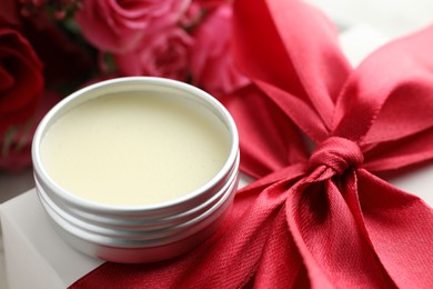 Photo of Natural solid perfume in container, gift box and flowers on table, closeup