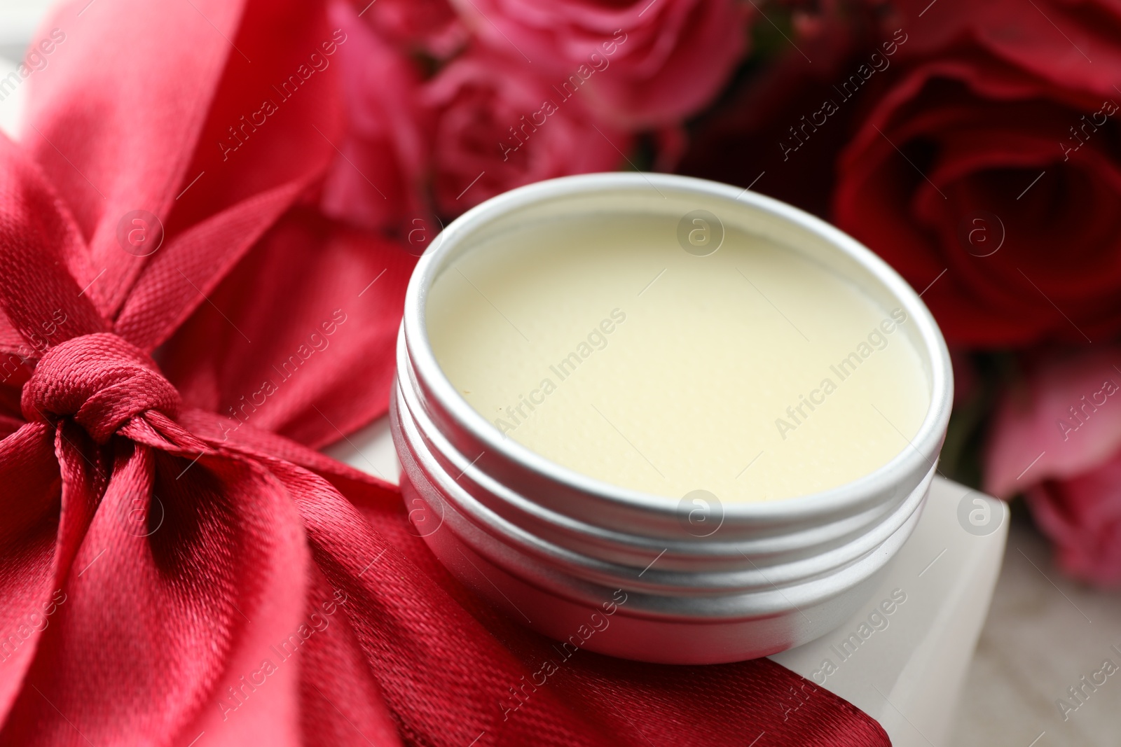 Photo of Natural solid perfume in container, gift box and flowers on table, closeup