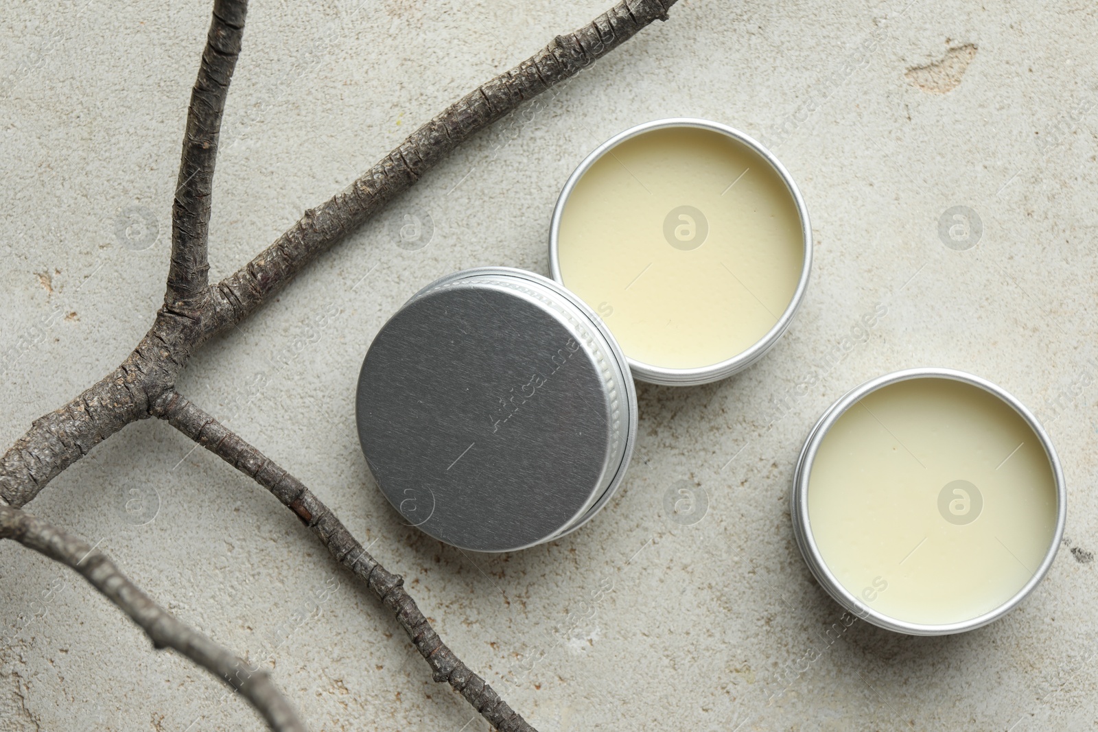 Photo of Natural solid perfume in containers and dry twigs on light table, flat lay