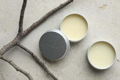 Photo of Natural solid perfume in containers and dry twigs on light table, flat lay