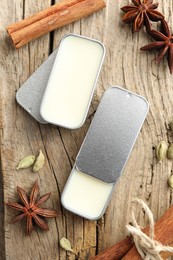 Photo of Natural solid perfume in containers and spices on wooden table, flat lay