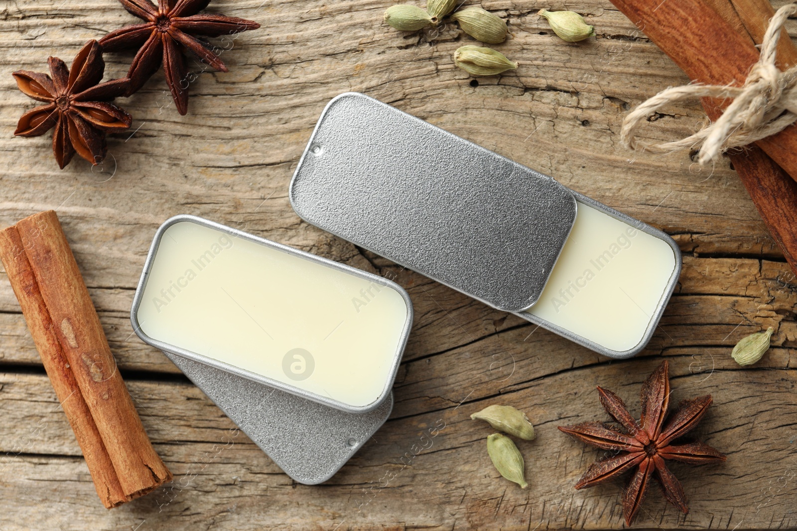 Photo of Natural solid perfume in containers and spices on wooden table, flat lay