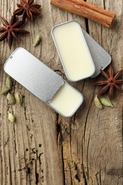 Photo of Natural solid perfume in containers and spices on wooden table, flat lay. Space for text