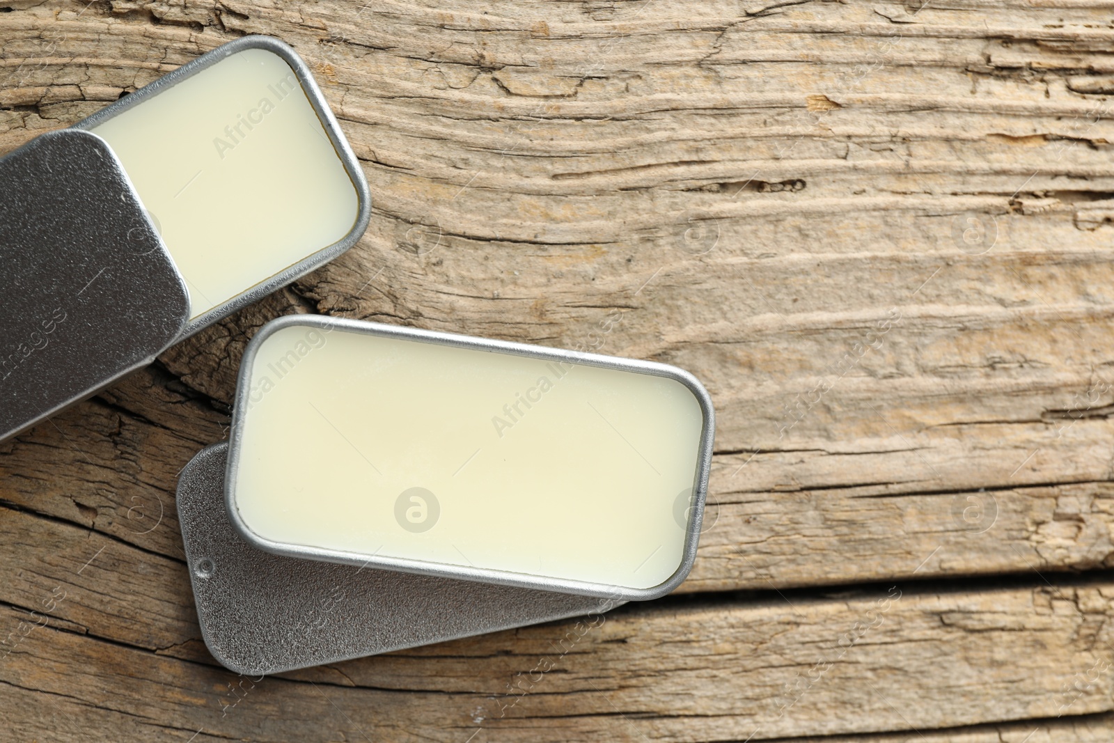 Photo of Natural solid perfume in containers on wooden table, flat lay. Space for text