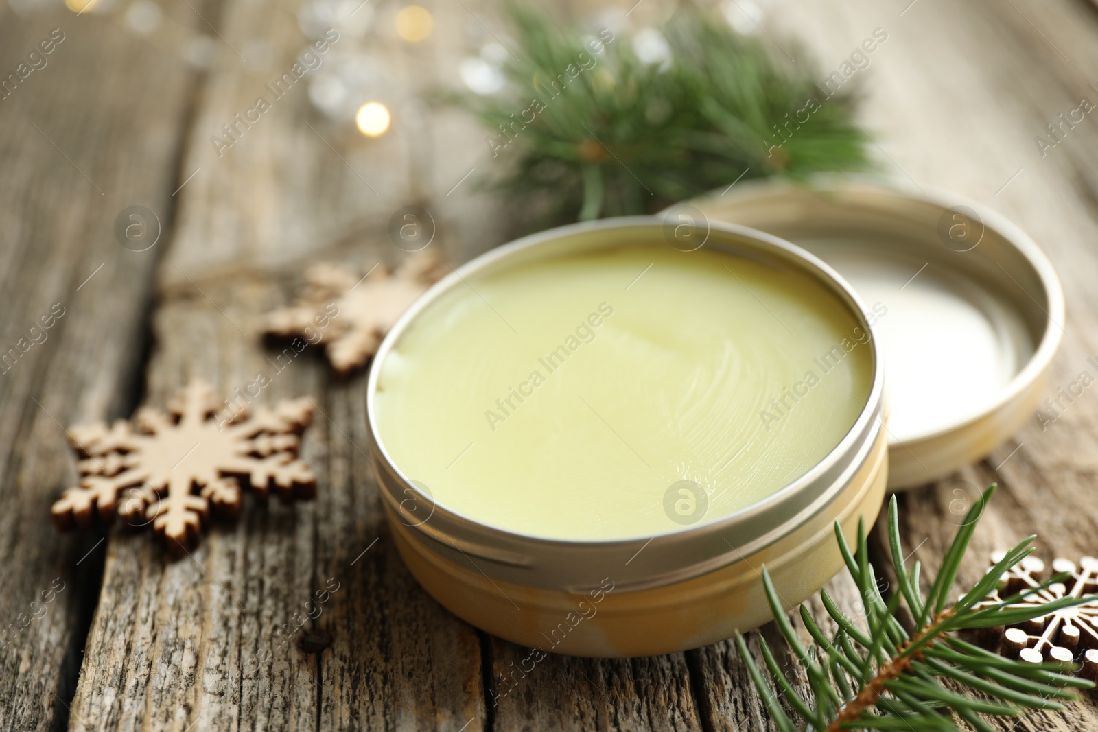 Photo of Natural solid perfume in container and Christmas decor on wooden table, closeup