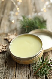 Photo of Natural solid perfume in container and Christmas decor on wooden table, closeup