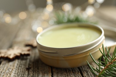 Photo of Natural solid perfume in container and fir on wooden table, closeup