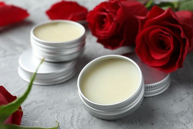 Photo of Natural solid perfume in containers and roses on grey table, closeup