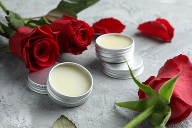 Photo of Natural solid perfume in containers and roses on grey table