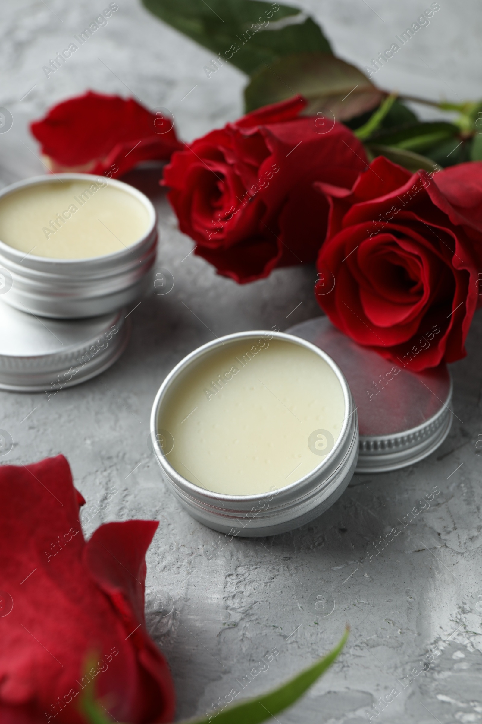 Photo of Natural solid perfume in containers and roses on grey table