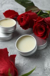 Photo of Natural solid perfume in containers and roses on grey table