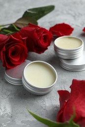 Photo of Natural solid perfume in containers and roses on grey table