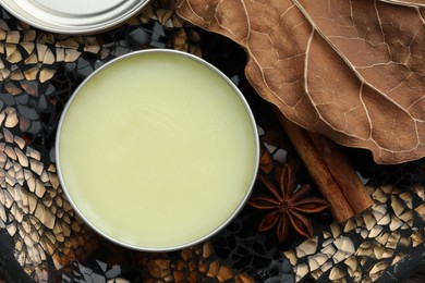 Photo of Natural solid perfume in container, spices and dry leaf on surface, flat lay