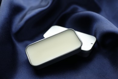 Photo of Natural solid perfume on blue silk fabric, closeup