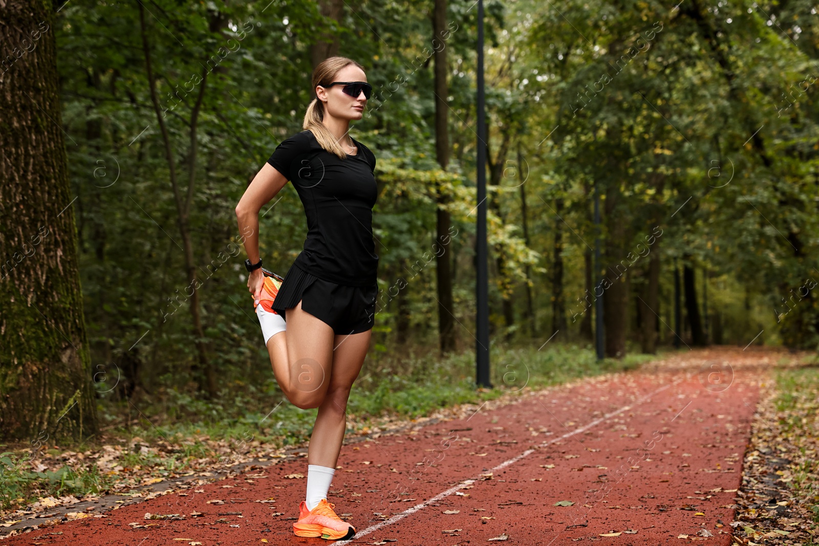 Photo of Young athletic woman stretching in park, space for text