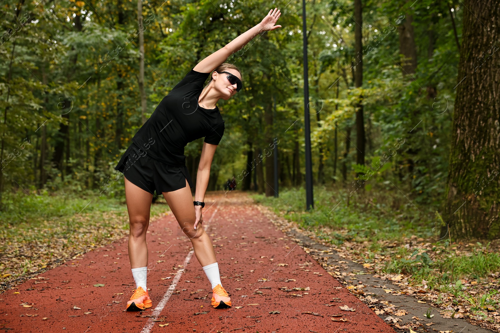 Photo of Young athletic woman stretching in park, space for text