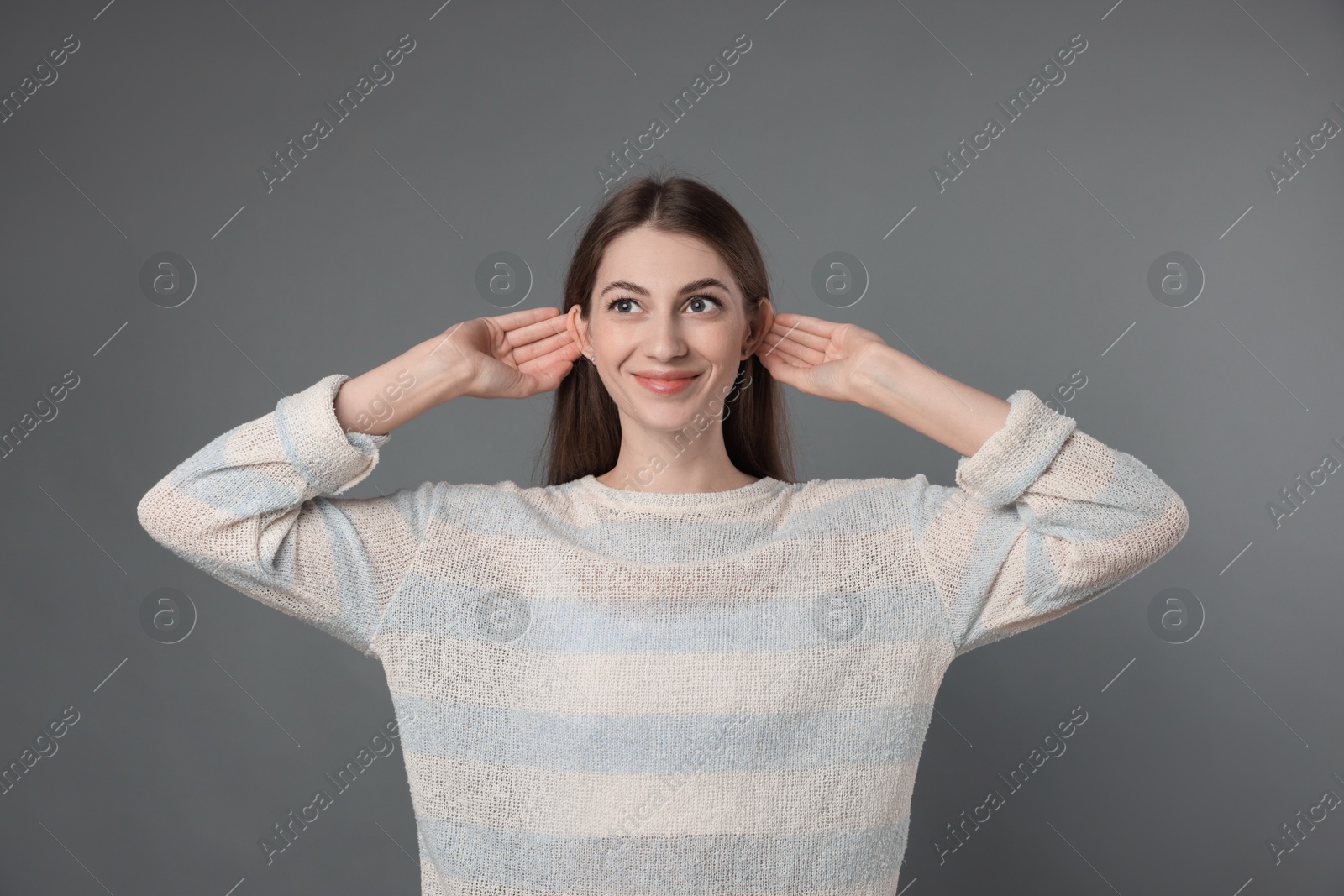 Photo of Woman showing hand to ear gesture on grey background