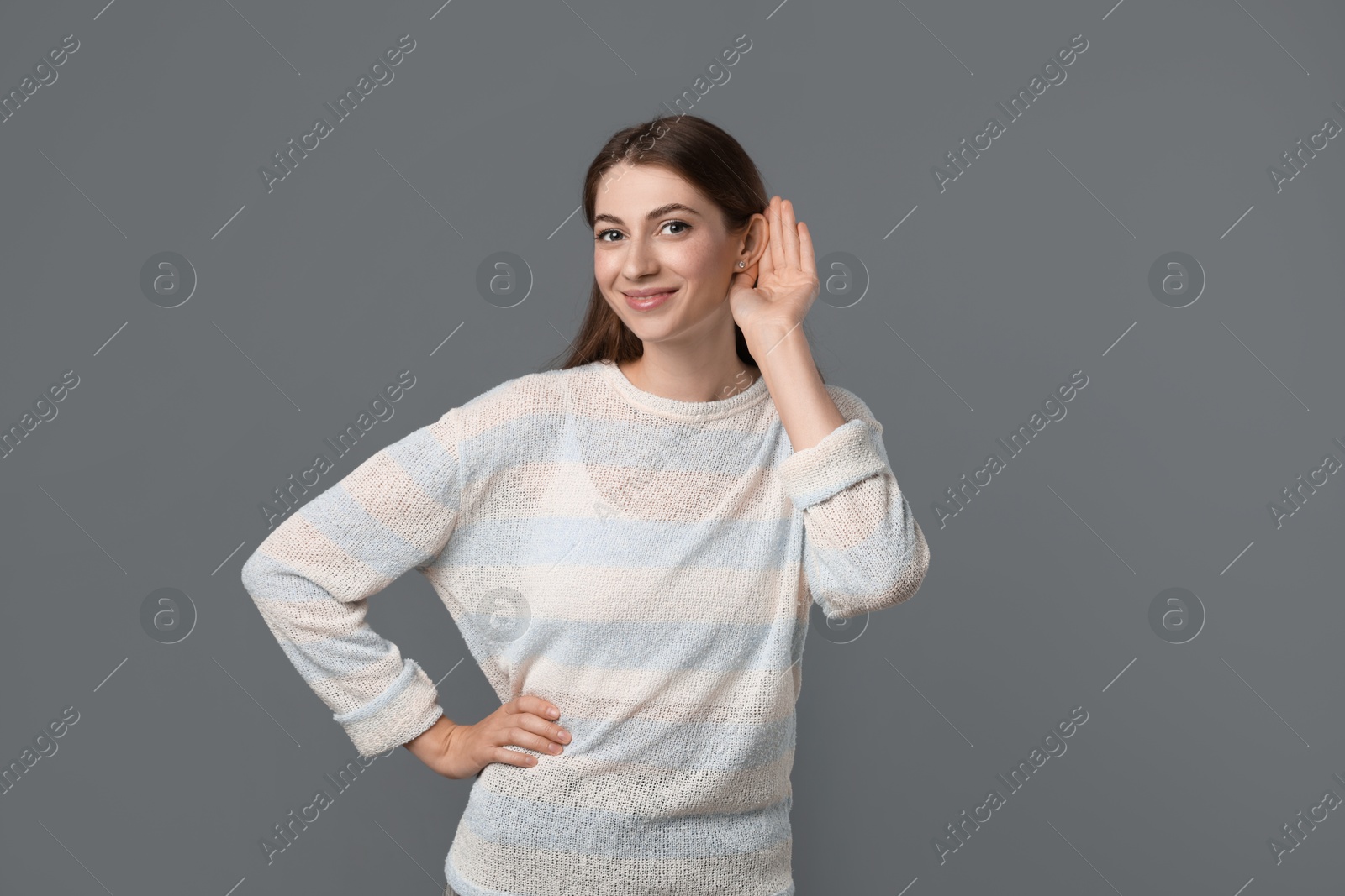 Photo of Woman showing hand to ear gesture on grey background