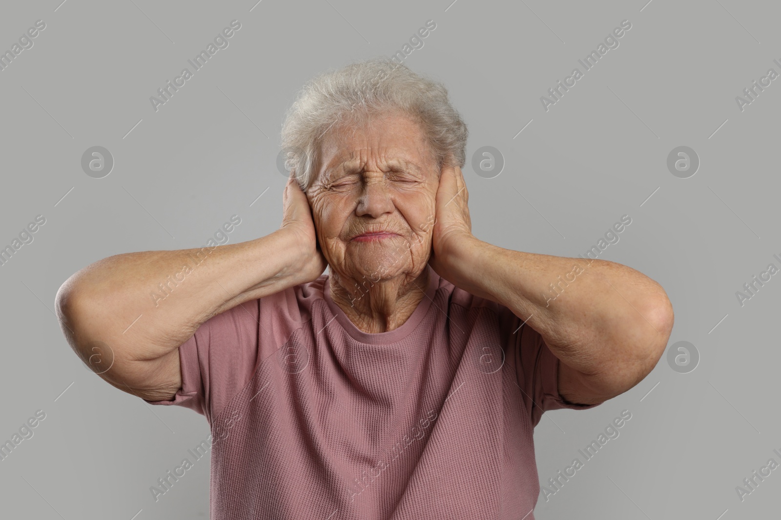 Photo of Senior woman covering her ears on grey background