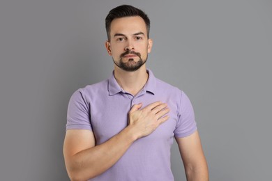 Photo of Man making promise on grey background. Oath gesture