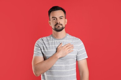 Photo of Man making promise on red background. Oath gesture